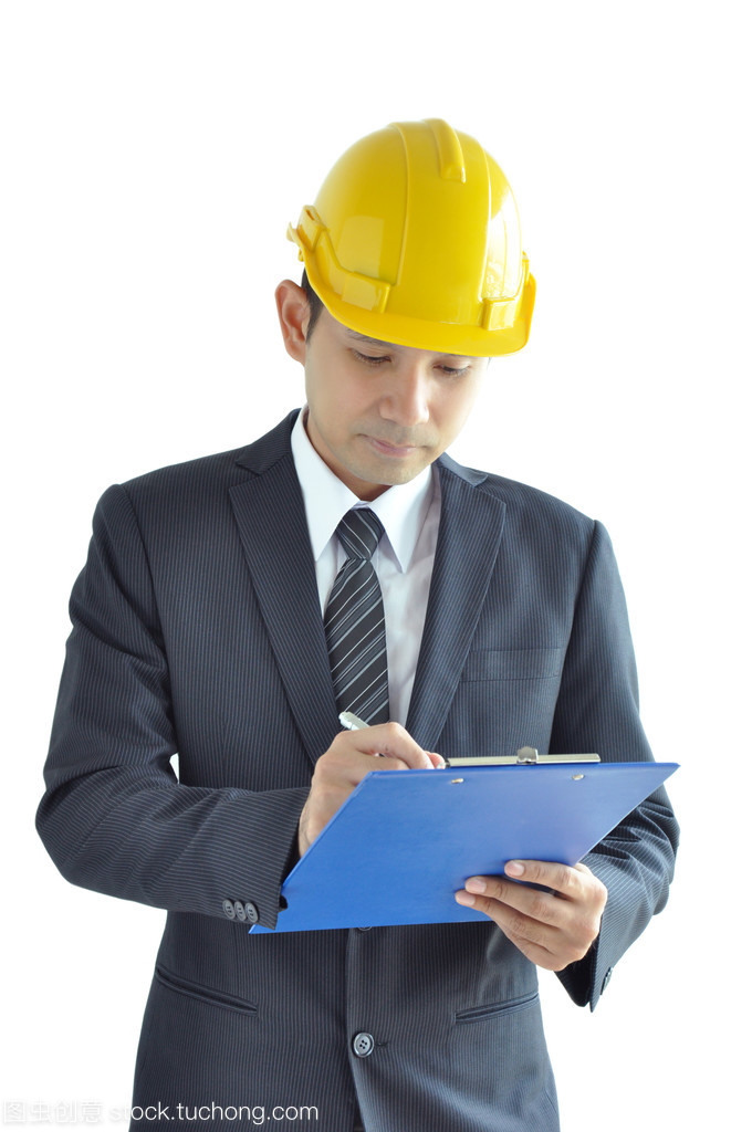 亚洲男子为建筑师或工程师穿西装 & 写作放在剪贴板上的安全帽